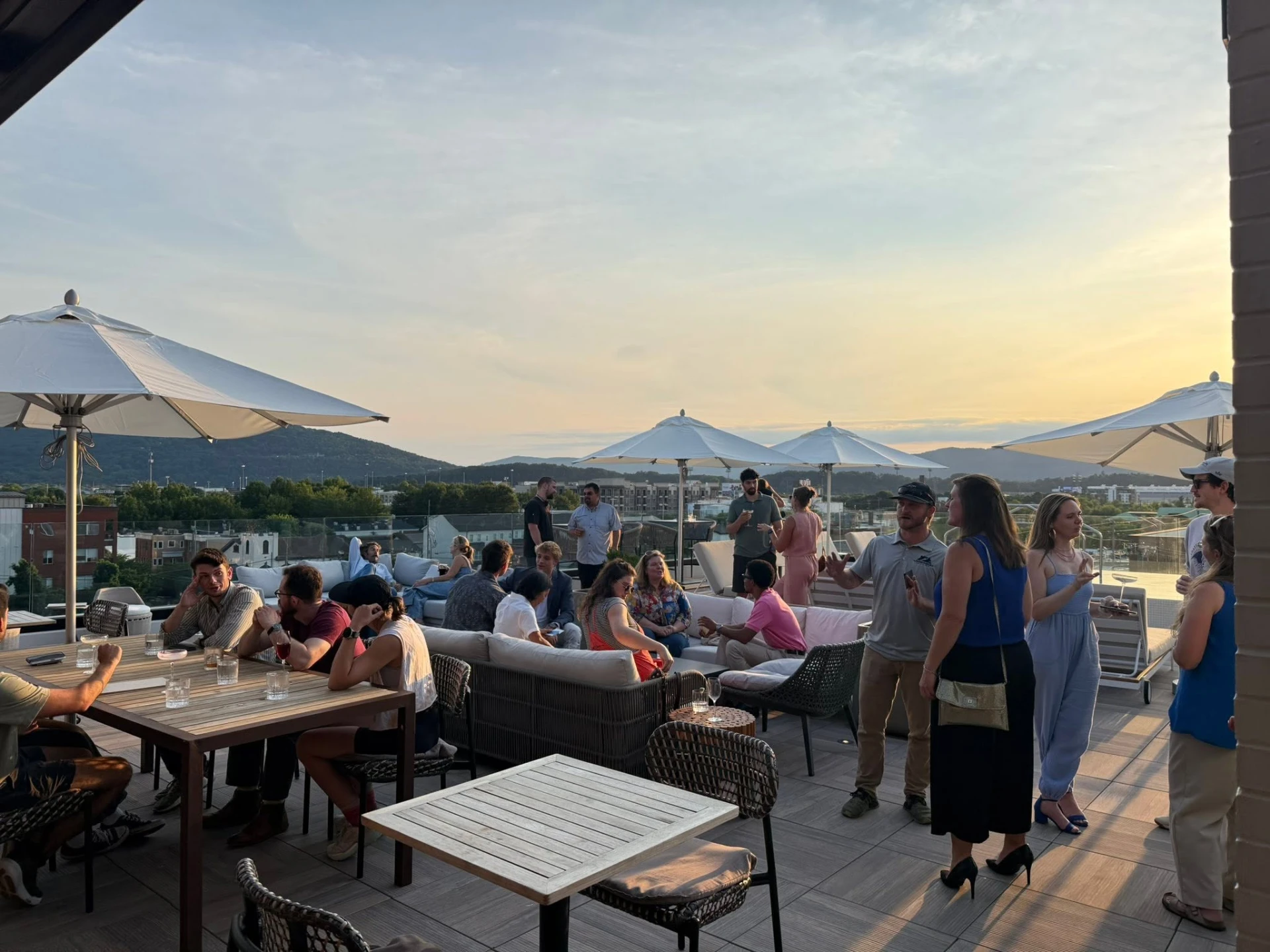 Chattanooga Entrepreneurs members talking on a rooftop at sunset with Lookout Mountain behind them